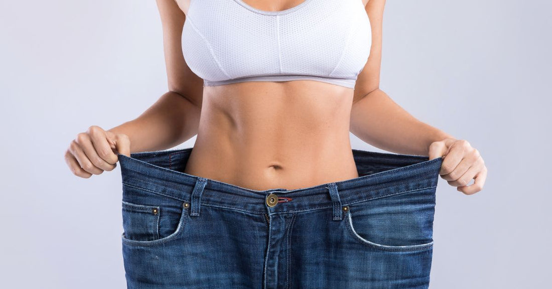 Woman wearing oversized jeans, symbolizing weight loss and body transformation