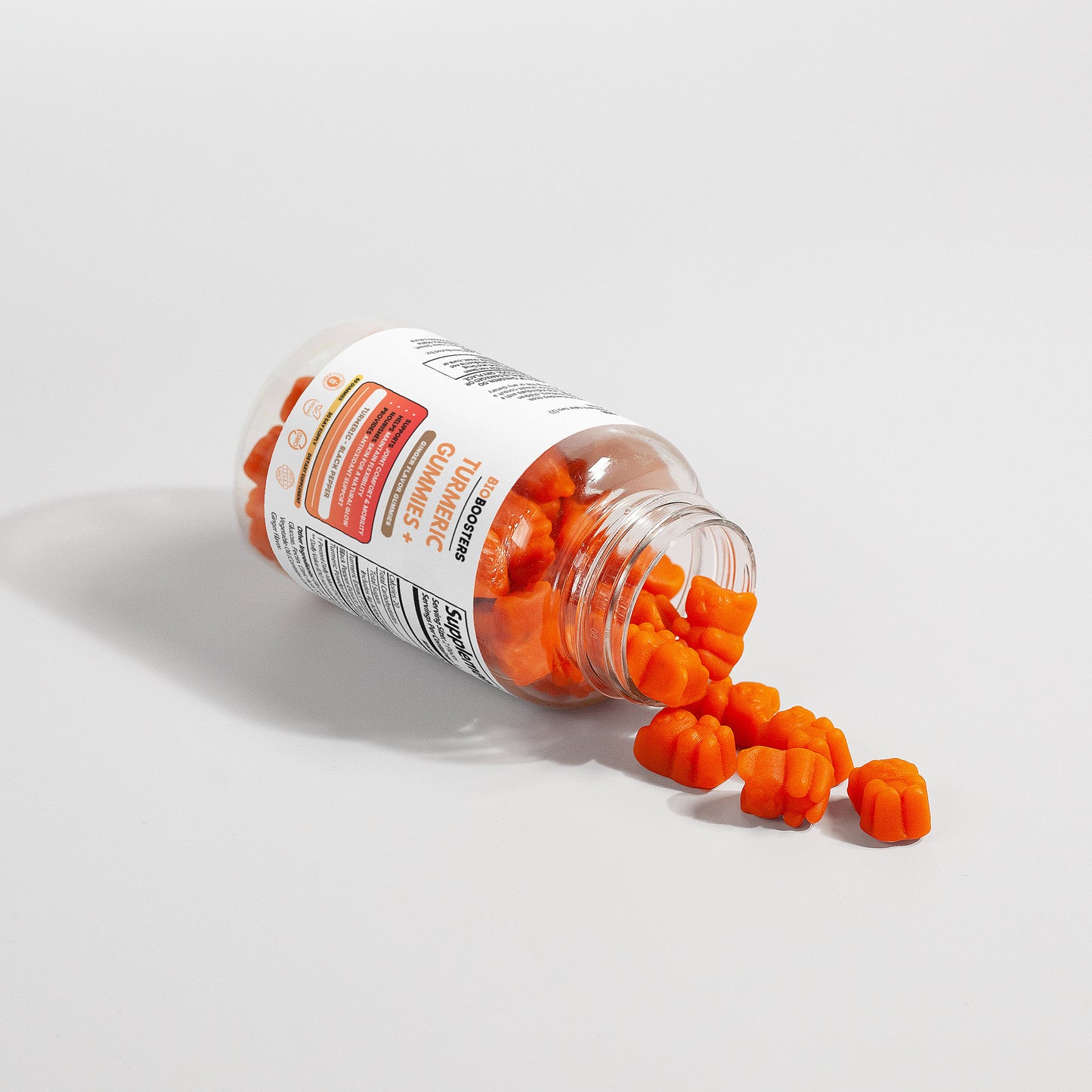 Bottle of orange supplements spilling out on a light gray background